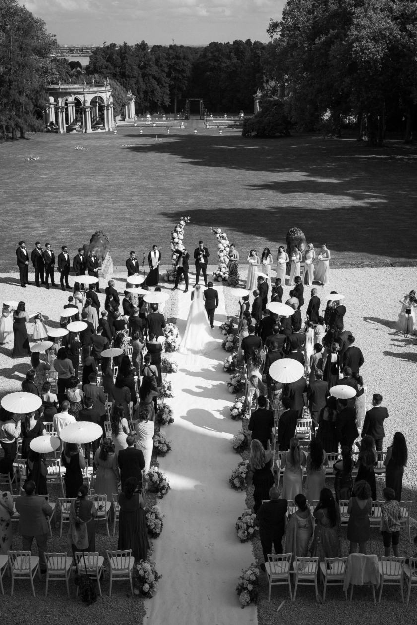 Bride walking down the aisle during a luxury outdoor wedding ceremony in France, captured by Olivier Neuville Photography.