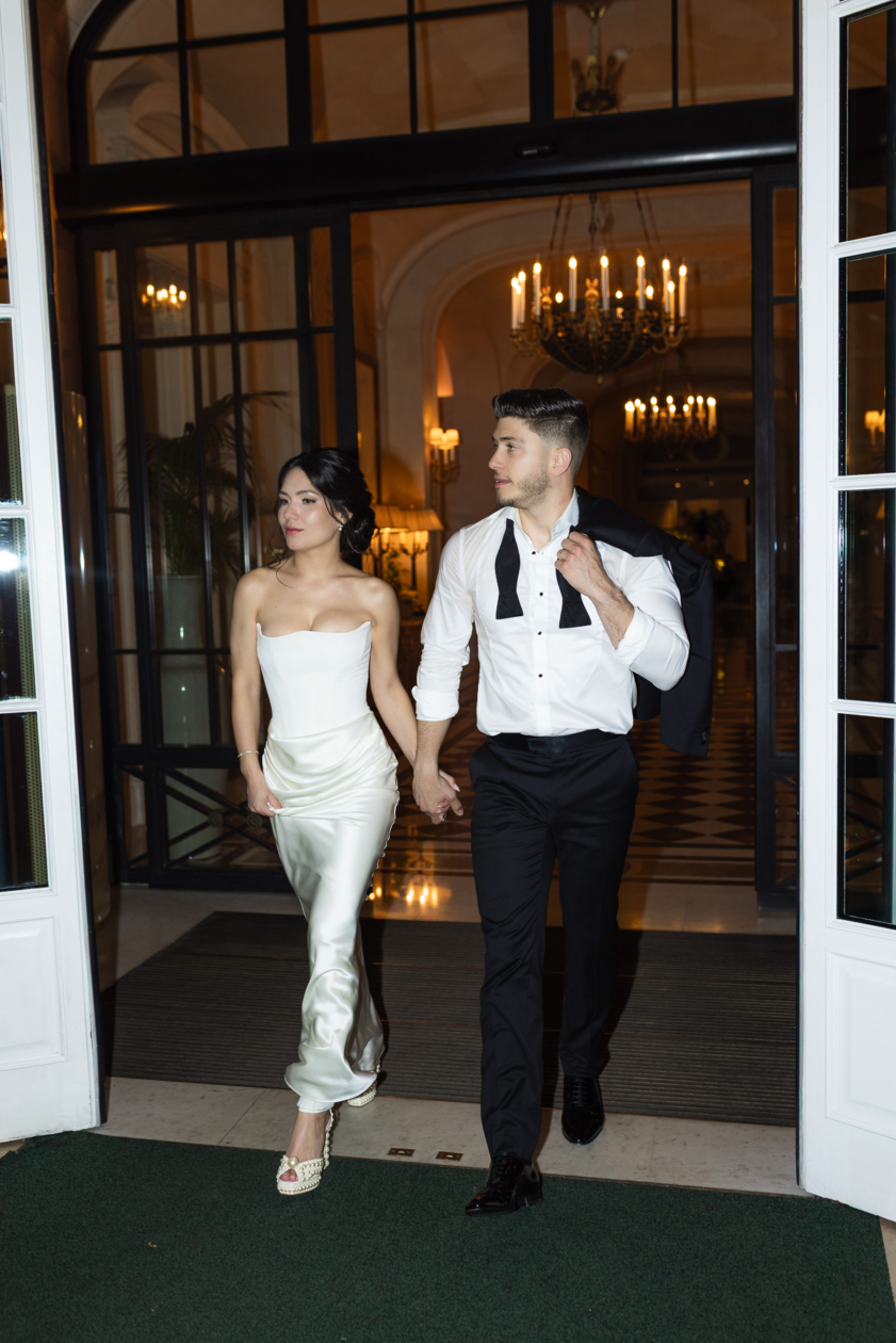 Stylish couple leaving a luxury Paris hotel hand in hand after their wedding celebration, captured by Olivier Neuville Photography.