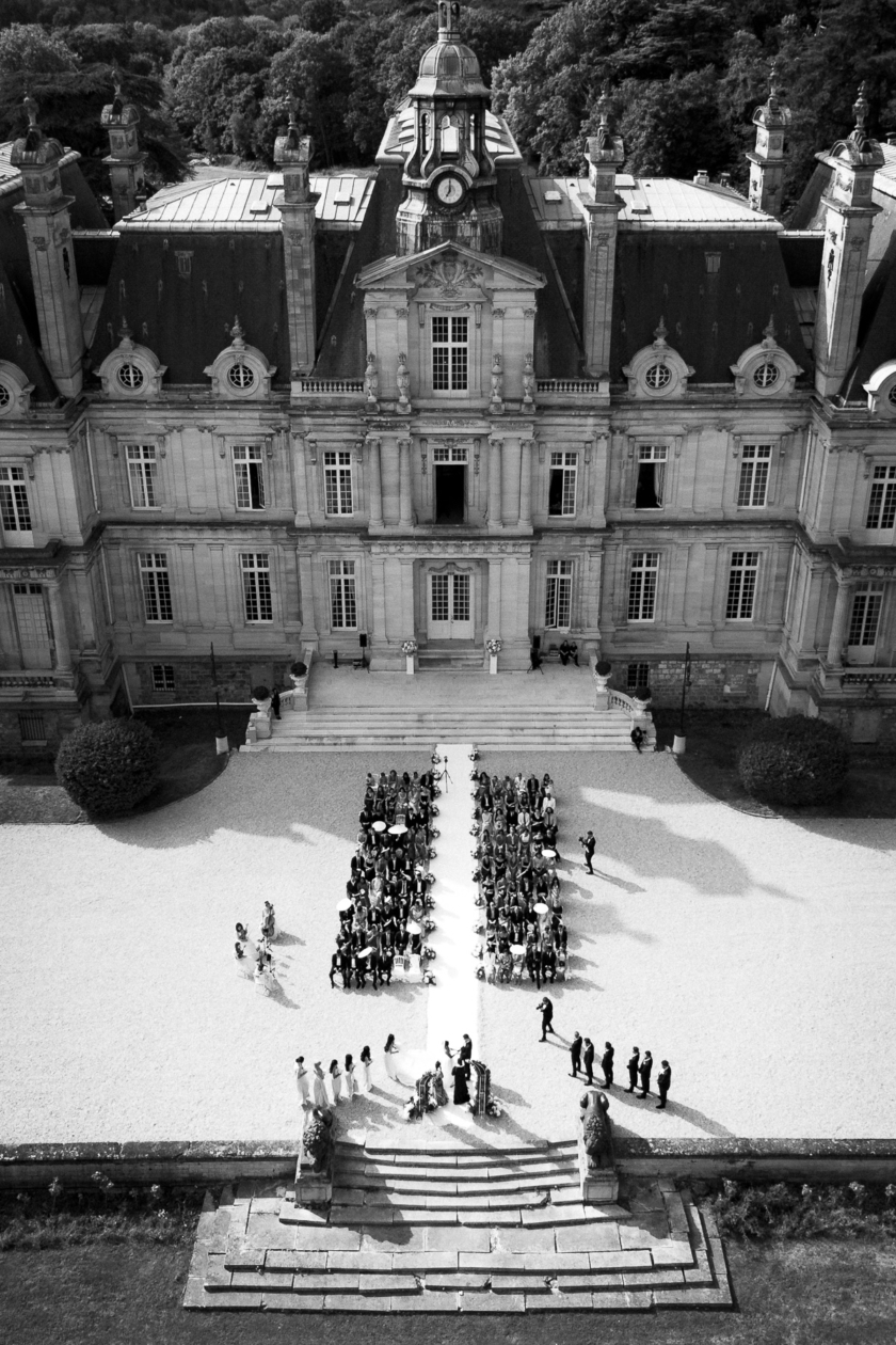 erial view of a luxury wedding ceremony in front of a French château, captured by Olivier Neuville Photography.