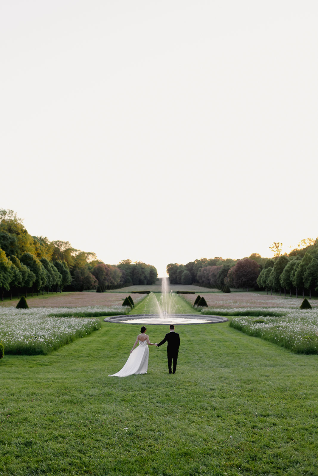 Romantic photo of the newlyweds strolling hand in hand in the picturesque gardens.